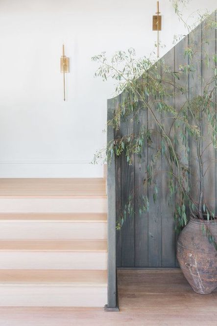 Thin candle sconces, antique ceramic vase, & vertical fence-like railing create a chic, yet rustic entry area. (Photography by Alyssa Rosenheck)