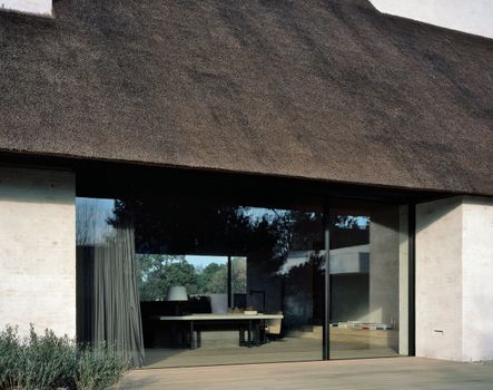 Large windows connect the living area of the home to the outside, where a swimming pool and nearby pool house reside | photograph by Hélène Binet