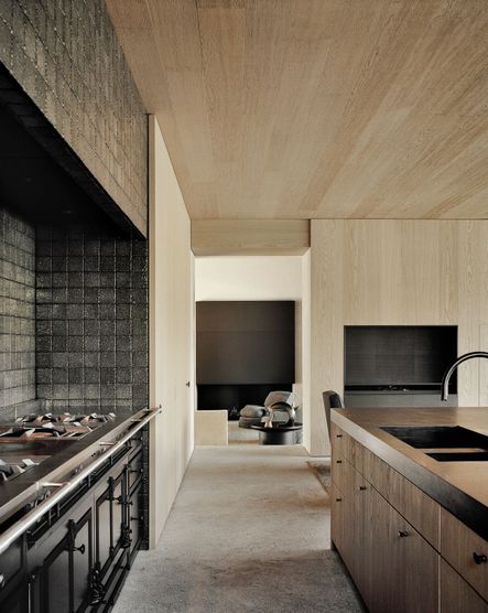 Slab-front cabinetry brings a soft touch to the kitchen, which contracts the black stone tile behind the stove | photograph by François Halard