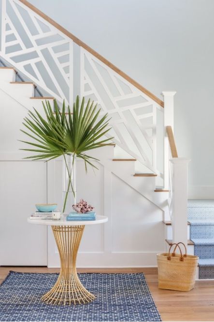 The entryway features an hourglass accent table on a woven blue rug.
