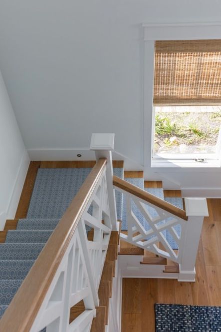 A muted blue runner adds comfort and functionality to this wood and white staircase.